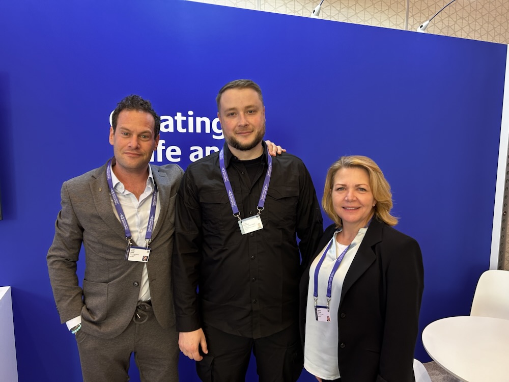 Three attendees at a conference backdrop